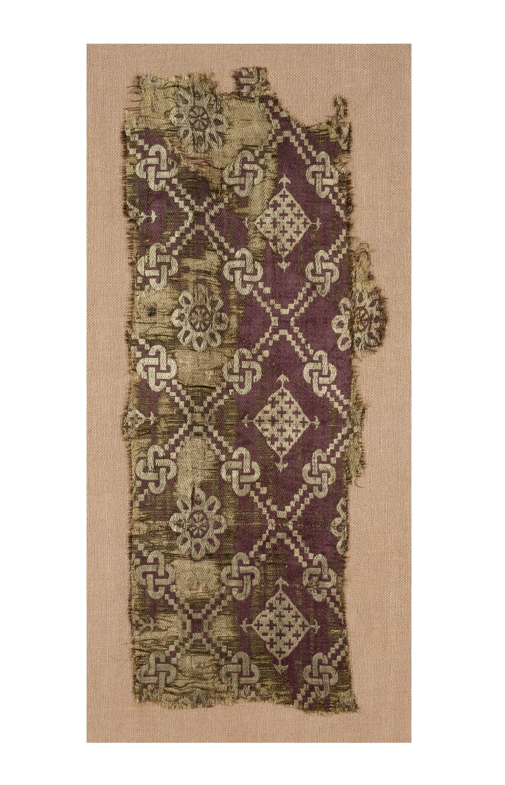 Silk fragment with white geometrical and floral patterns against a purple background, for comparison with the seal bag.